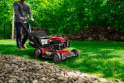Photo of a red Craftsman lawn mower CM11A-A2C2093 in use on grass, side view outdoors with trees in background.